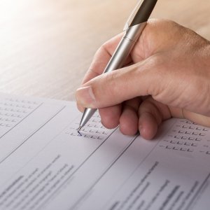 Hand mit Stift schreibt auf einem Blatt Papier